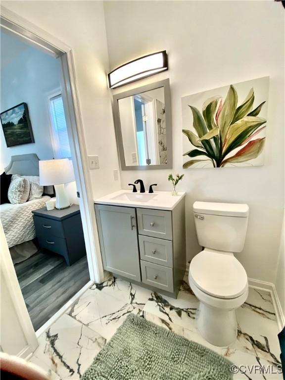 bathroom featuring marble finish floor, toilet, vanity, and baseboards