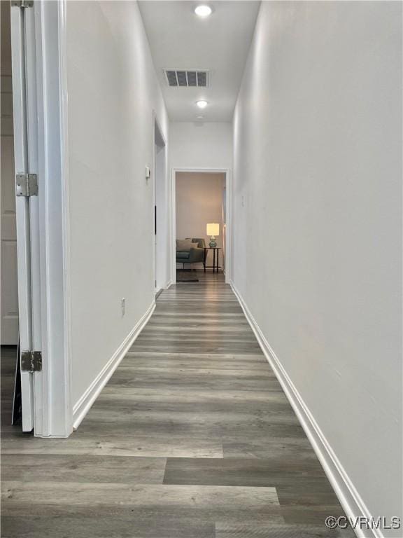 corridor with wood finished floors, visible vents, and baseboards