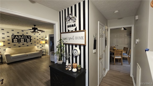 hall featuring visible vents, dark wood-style flooring, and a textured ceiling