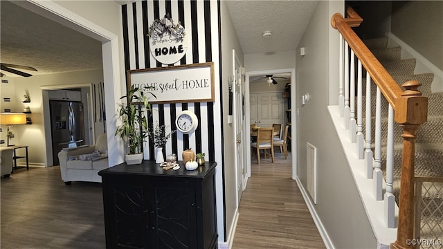 hall featuring visible vents, a textured ceiling, dark wood-style floors, stairway, and baseboards