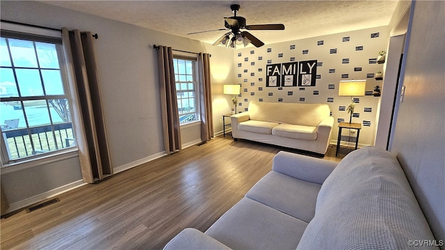 living area with wood finished floors, baseboards, visible vents, ceiling fan, and a textured ceiling