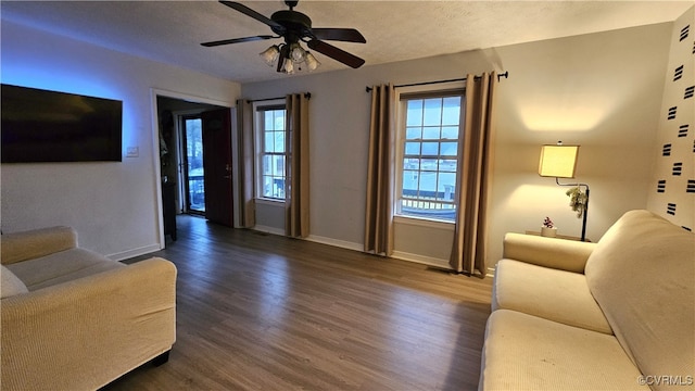 living area featuring wood finished floors, visible vents, baseboards, ceiling fan, and a textured ceiling