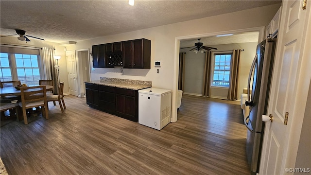 kitchen featuring fridge, light countertops, dark wood-type flooring, and freestanding refrigerator