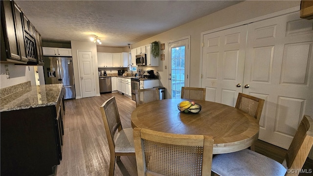 dining space featuring dark wood-type flooring and a textured ceiling