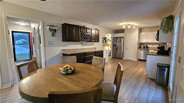 dining room featuring light wood-style flooring and a textured ceiling