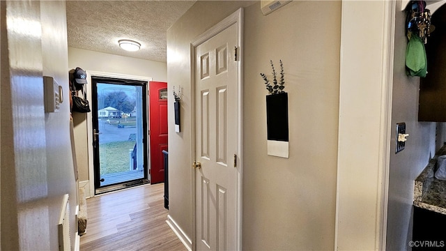 hall with wood finished floors, visible vents, and a textured ceiling