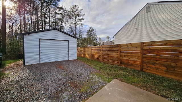 detached garage featuring driveway and fence