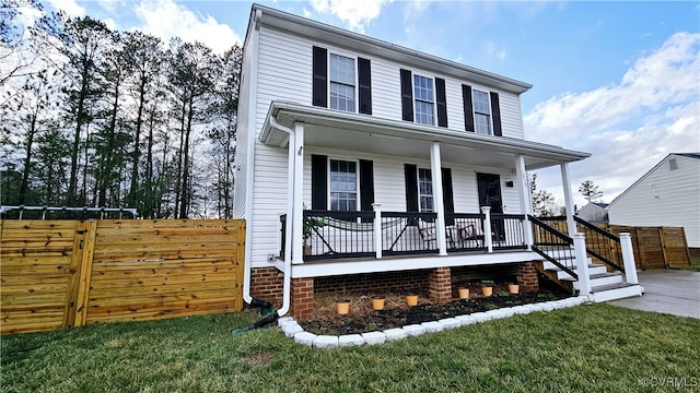 view of front of house featuring covered porch, a front yard, and fence