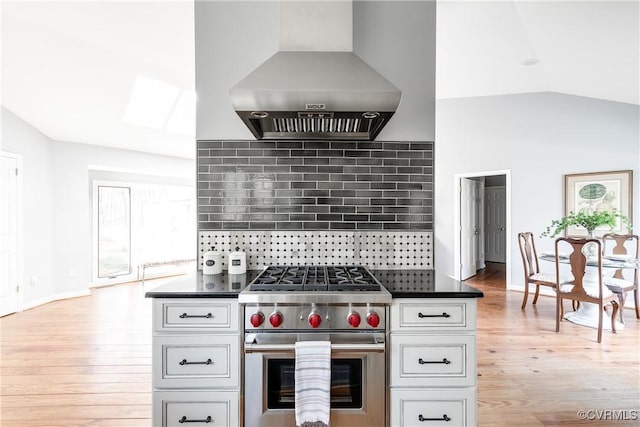 kitchen featuring dark countertops, designer stove, island exhaust hood, and vaulted ceiling