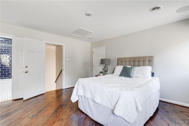 bedroom with attic access, visible vents, baseboards, and wood finished floors