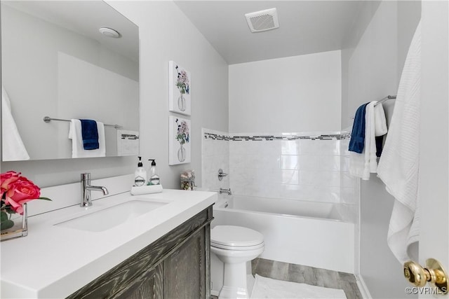 bathroom featuring toilet, wood finished floors, vanity, visible vents, and a bathtub