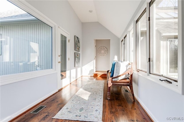 hall featuring baseboards, visible vents, vaulted ceiling, and dark wood-style flooring