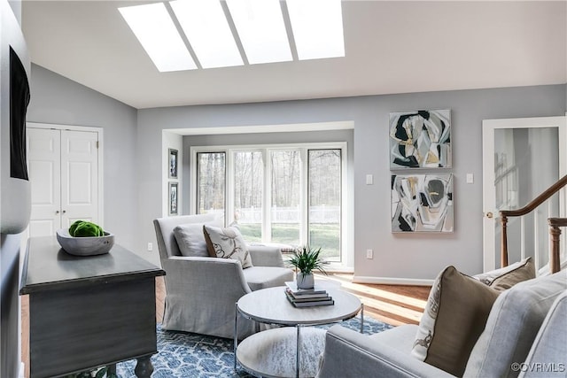 living area featuring lofted ceiling with skylight, stairs, and wood finished floors