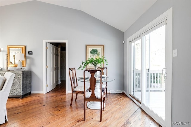 dining area with light wood-style floors, visible vents, vaulted ceiling, and baseboards