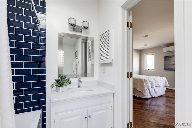 ensuite bathroom with ensuite bathroom, wood finished floors, vanity, an AC wall unit, and a bath