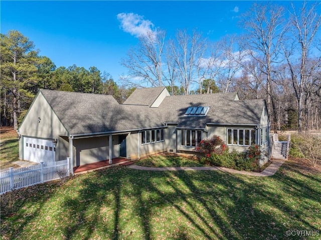 view of front of property with an attached garage, roof with shingles, a front yard, and fence