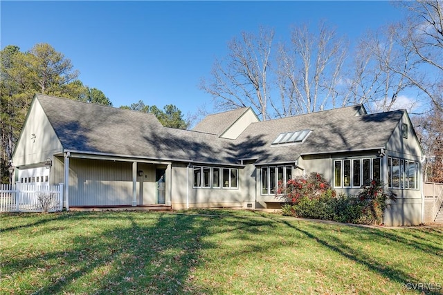 view of front of home featuring a garage, roof with shingles, fence, and a front yard