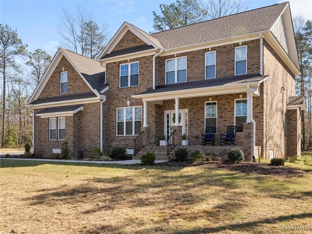 craftsman house featuring covered porch, a front lawn, a shingled roof, and brick siding