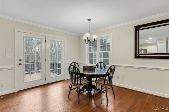 dining room with a chandelier, crown molding, baseboards, and wood finished floors