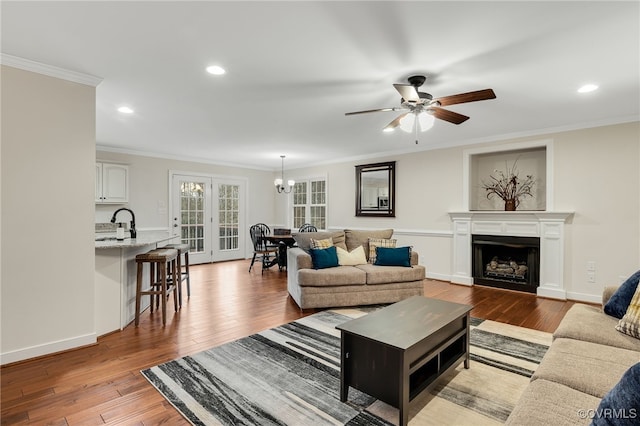 living room with hardwood / wood-style flooring, recessed lighting, a fireplace, baseboards, and ornamental molding