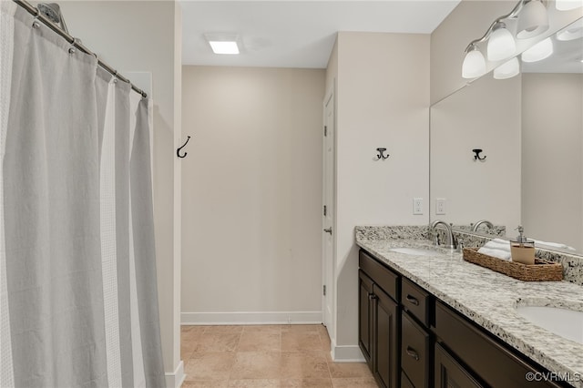 bathroom with double vanity, a sink, and baseboards