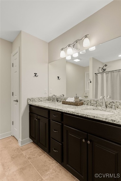 bathroom with double vanity, a shower with shower curtain, a sink, and baseboards