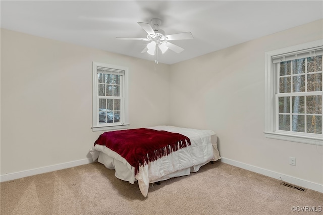 carpeted bedroom featuring baseboards, visible vents, and a ceiling fan