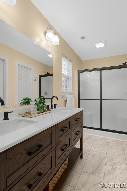 full bath with double vanity, marble finish floor, a shower stall, and a sink