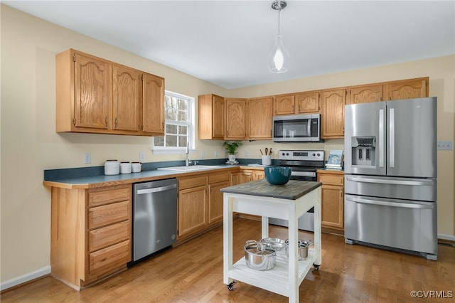 kitchen featuring a sink, baseboards, appliances with stainless steel finishes, light wood-type flooring, and pendant lighting