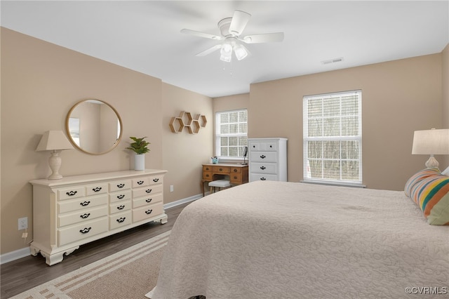 bedroom with dark wood-style floors, visible vents, baseboards, and a ceiling fan