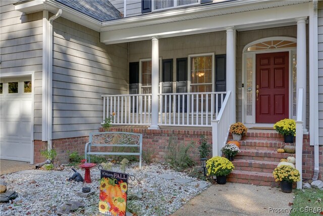 doorway to property with a porch, roof with shingles, and an attached garage