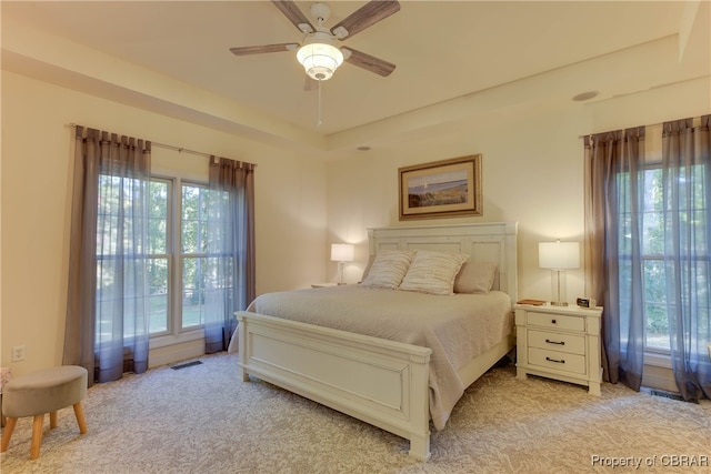 bedroom featuring light carpet, ceiling fan, multiple windows, and visible vents