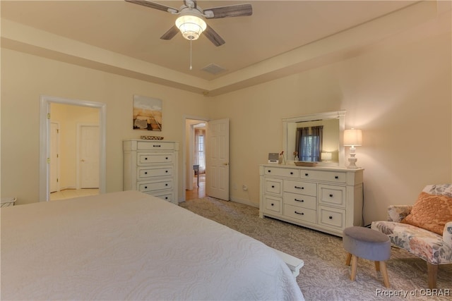 bedroom featuring a tray ceiling, visible vents, a ceiling fan, and light colored carpet