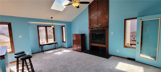 unfurnished living room with carpet floors, a skylight, a fireplace, and high vaulted ceiling