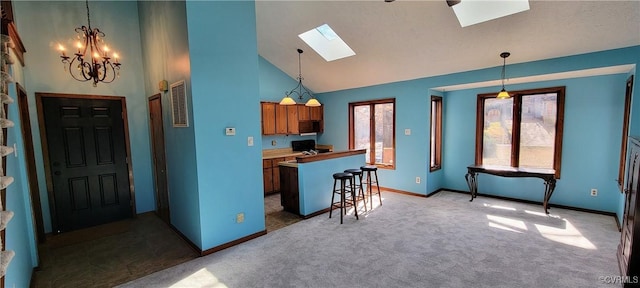 kitchen with a skylight, visible vents, brown cabinetry, carpet flooring, and high vaulted ceiling