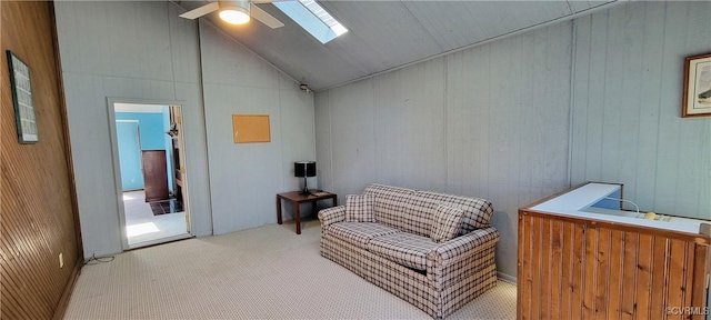 sitting room featuring vaulted ceiling with skylight, carpet flooring, and a ceiling fan