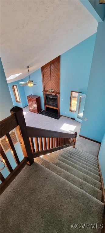 staircase featuring carpet flooring, vaulted ceiling, a textured ceiling, and ceiling fan