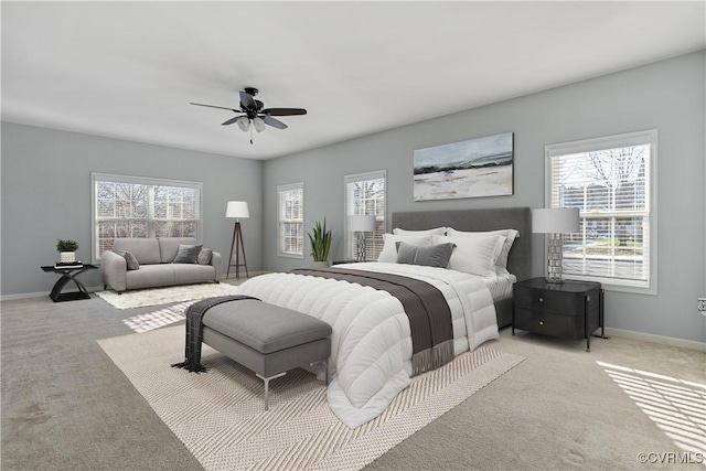 bedroom featuring light carpet, multiple windows, a ceiling fan, and baseboards