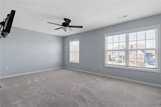 carpeted spare room with a ceiling fan, visible vents, and baseboards