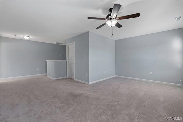 empty room with a ceiling fan, light colored carpet, visible vents, and baseboards