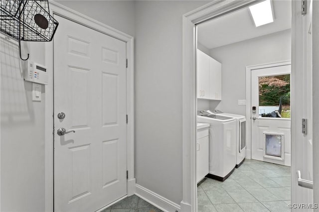 washroom featuring cabinet space, light tile patterned flooring, baseboards, and washing machine and clothes dryer