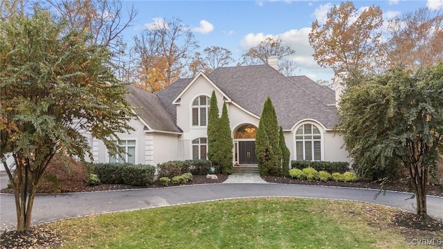 view of front of house featuring a front yard, a chimney, and stucco siding