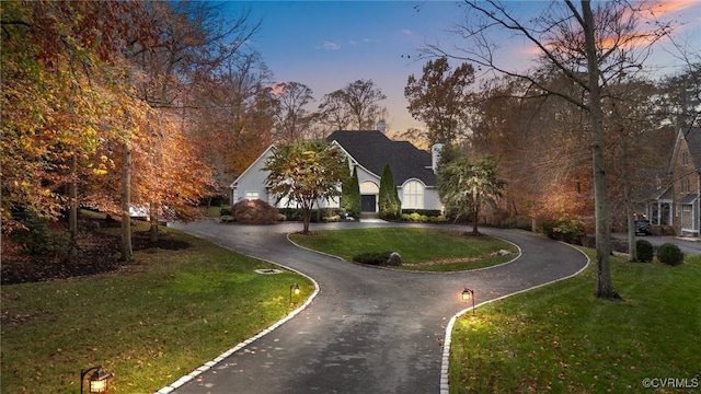 french country home with curved driveway and a lawn