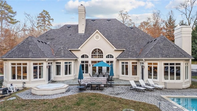 back of property with an outdoor hangout area, a patio, a chimney, and an outdoor pool