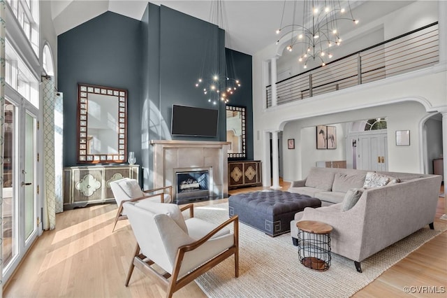 living room with arched walkways, a towering ceiling, and wood finished floors