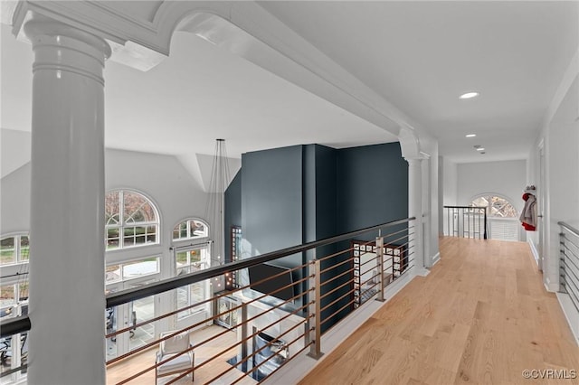 corridor with recessed lighting, decorative columns, wood finished floors, and an upstairs landing