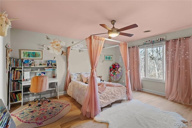 bedroom featuring ceiling fan, wood finished floors, visible vents, and baseboards