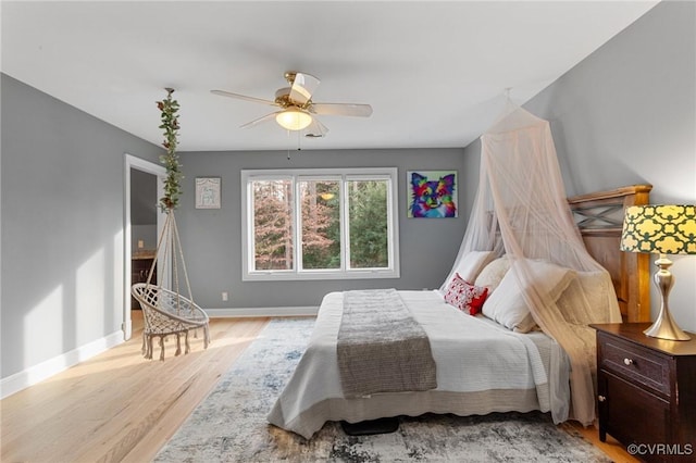 bedroom featuring a ceiling fan, light wood-style flooring, and baseboards