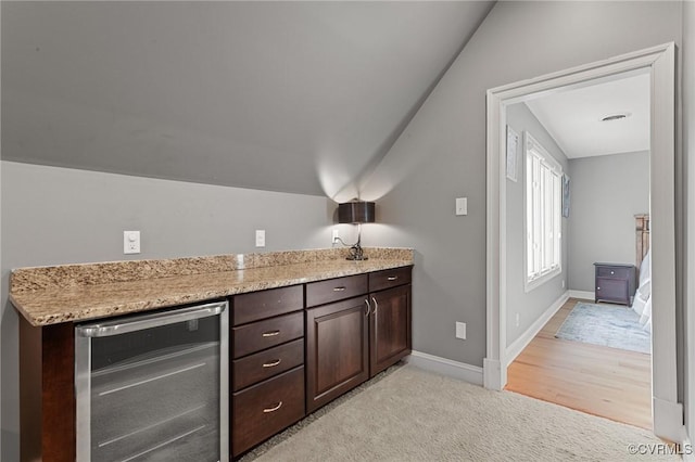 bar featuring beverage cooler, light colored carpet, vaulted ceiling, and baseboards