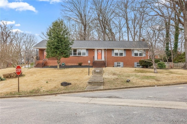 ranch-style house featuring brick siding, fence, and a front lawn